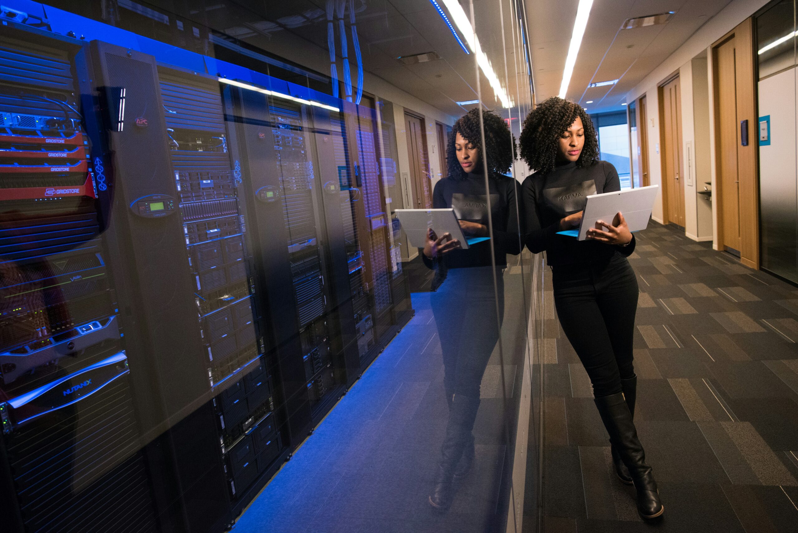 Woman in a server room typing on her laptop