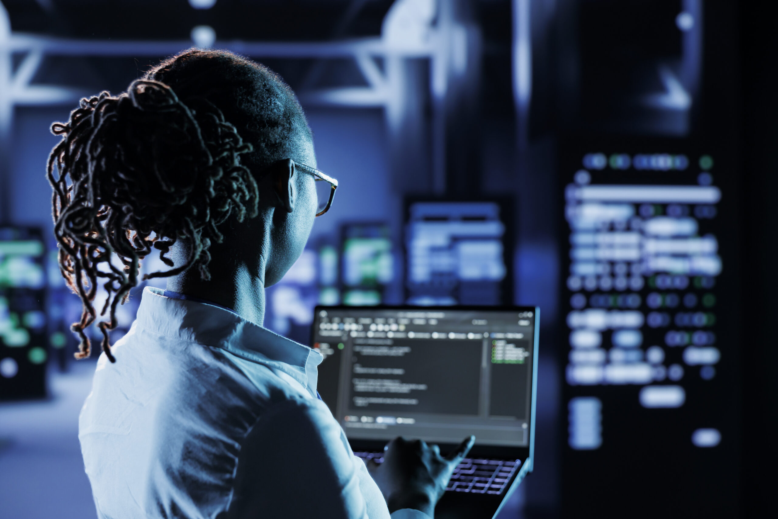 Woman in a server room typing on her laptop