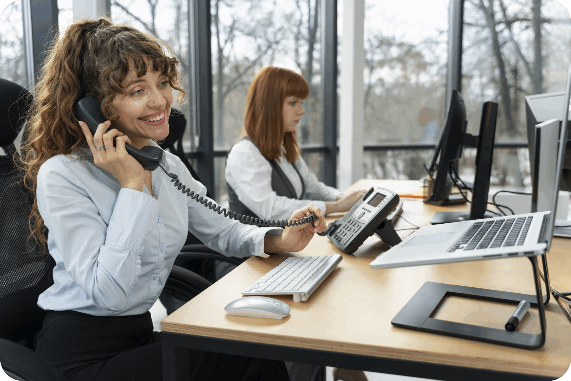 Office employees using VoIP phones and computers for business communication in a modern workspace.
