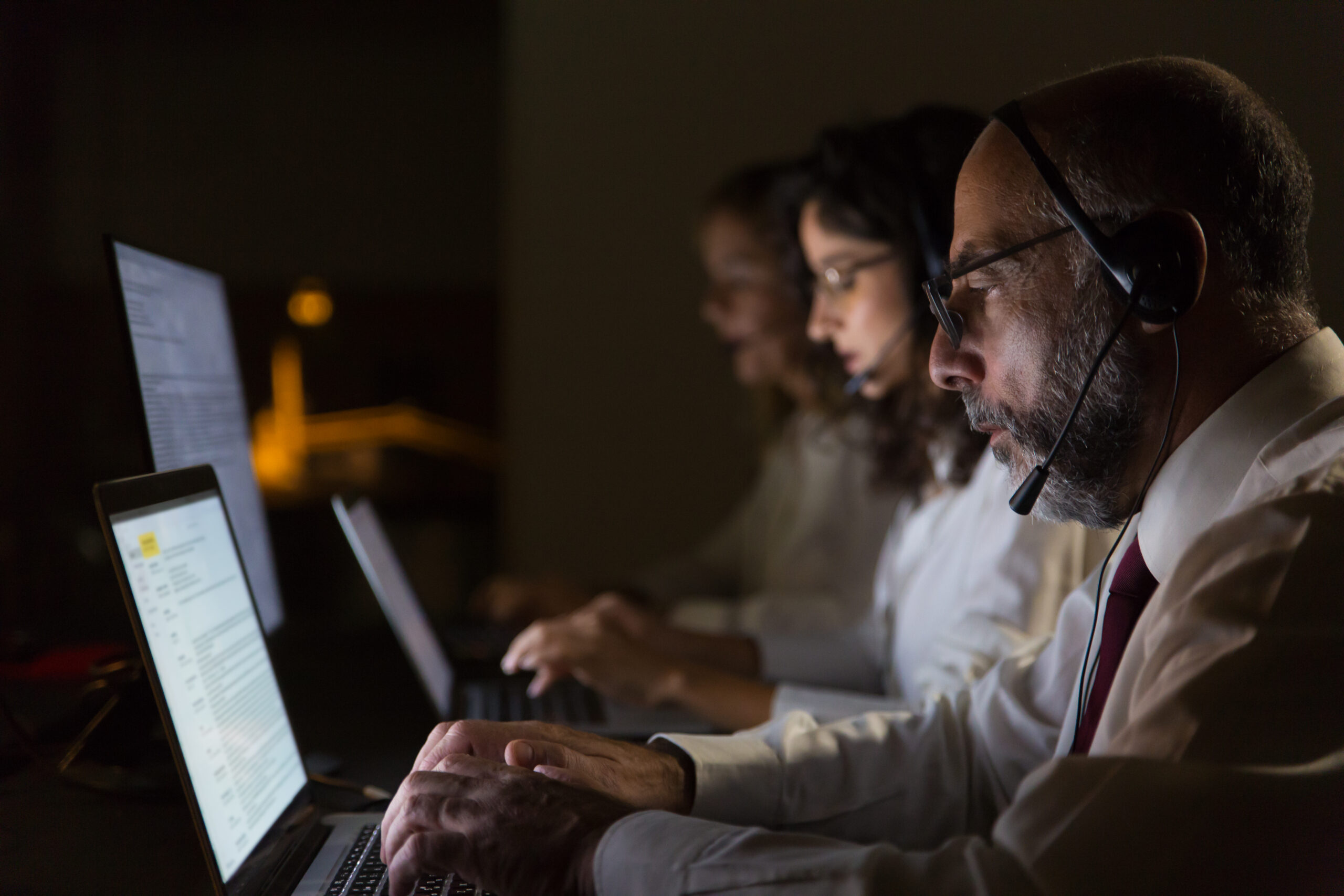 IT support staff wearing headsets working late at computers
