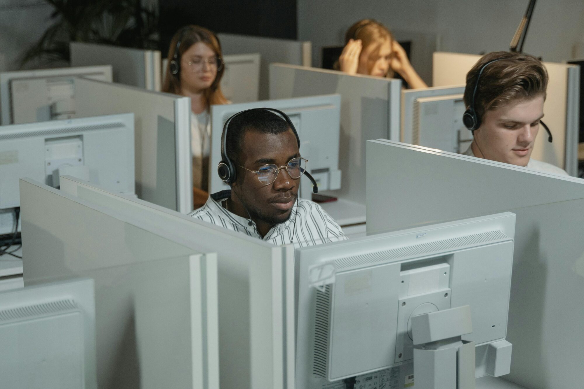 IT support specialist with headset working in white cubicle