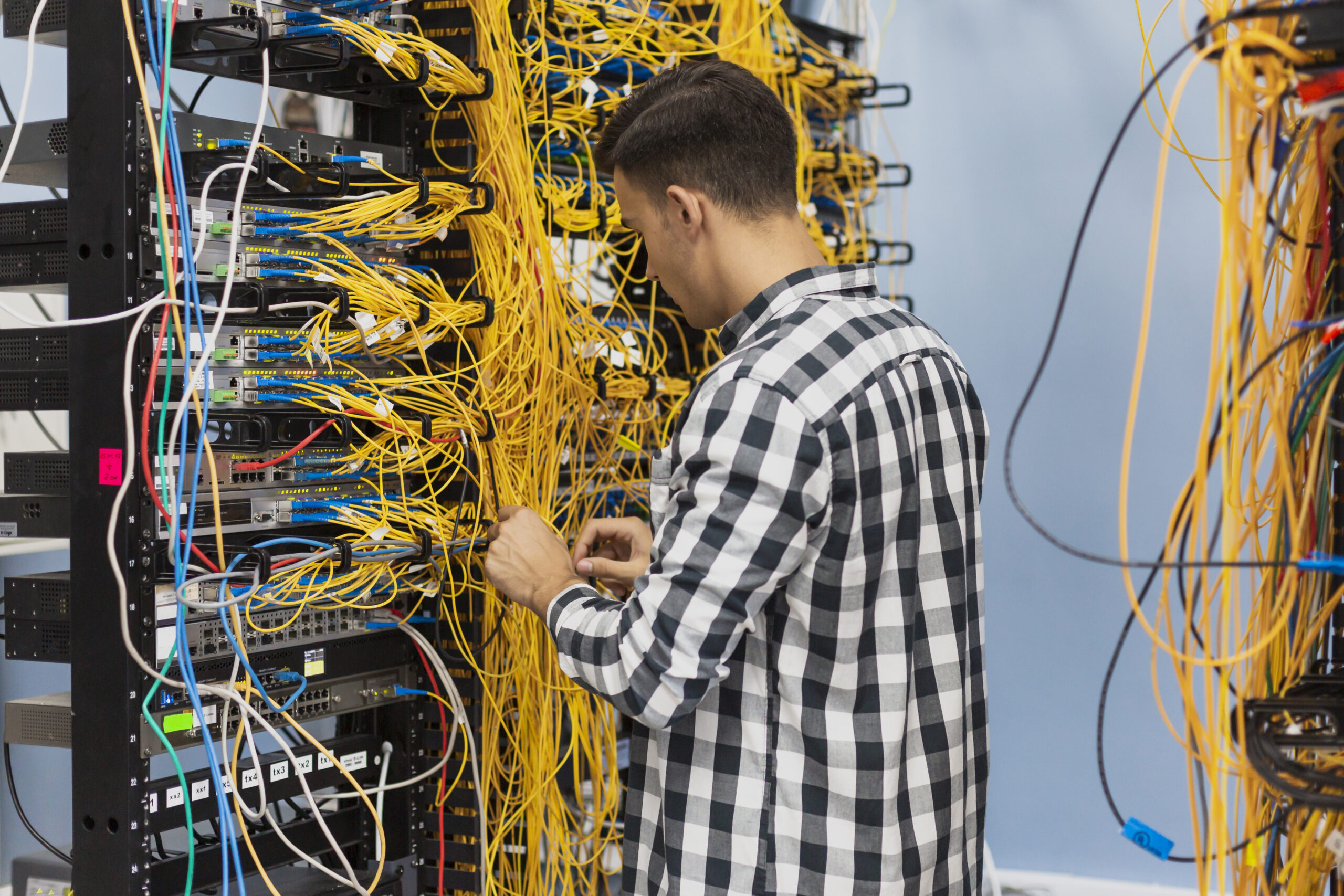 Technician organizing tangled network cables in server rack