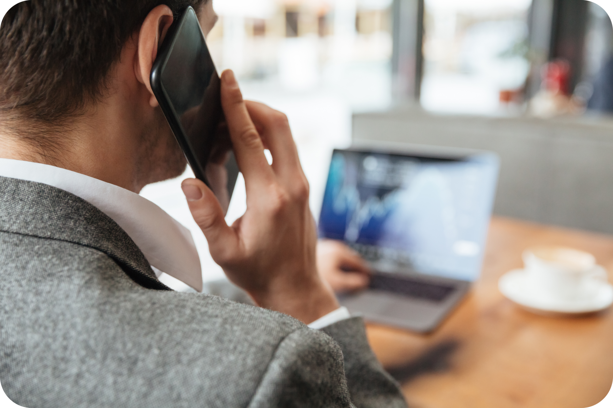 Suited businessman taking a phone call while working on a laptop