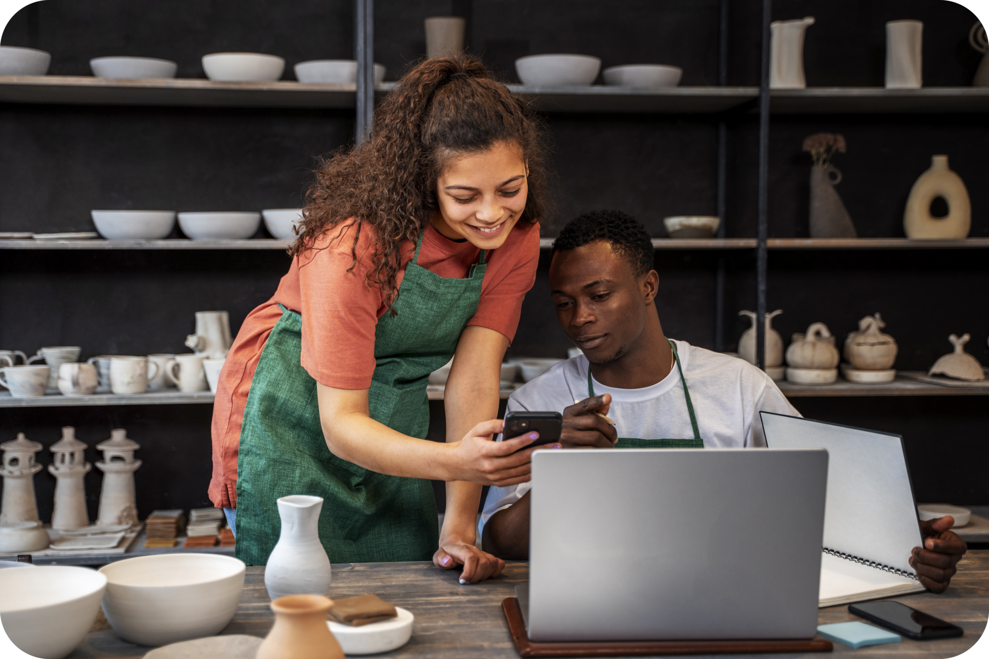 Small business owners sharing smartphone data at a craft workshop
