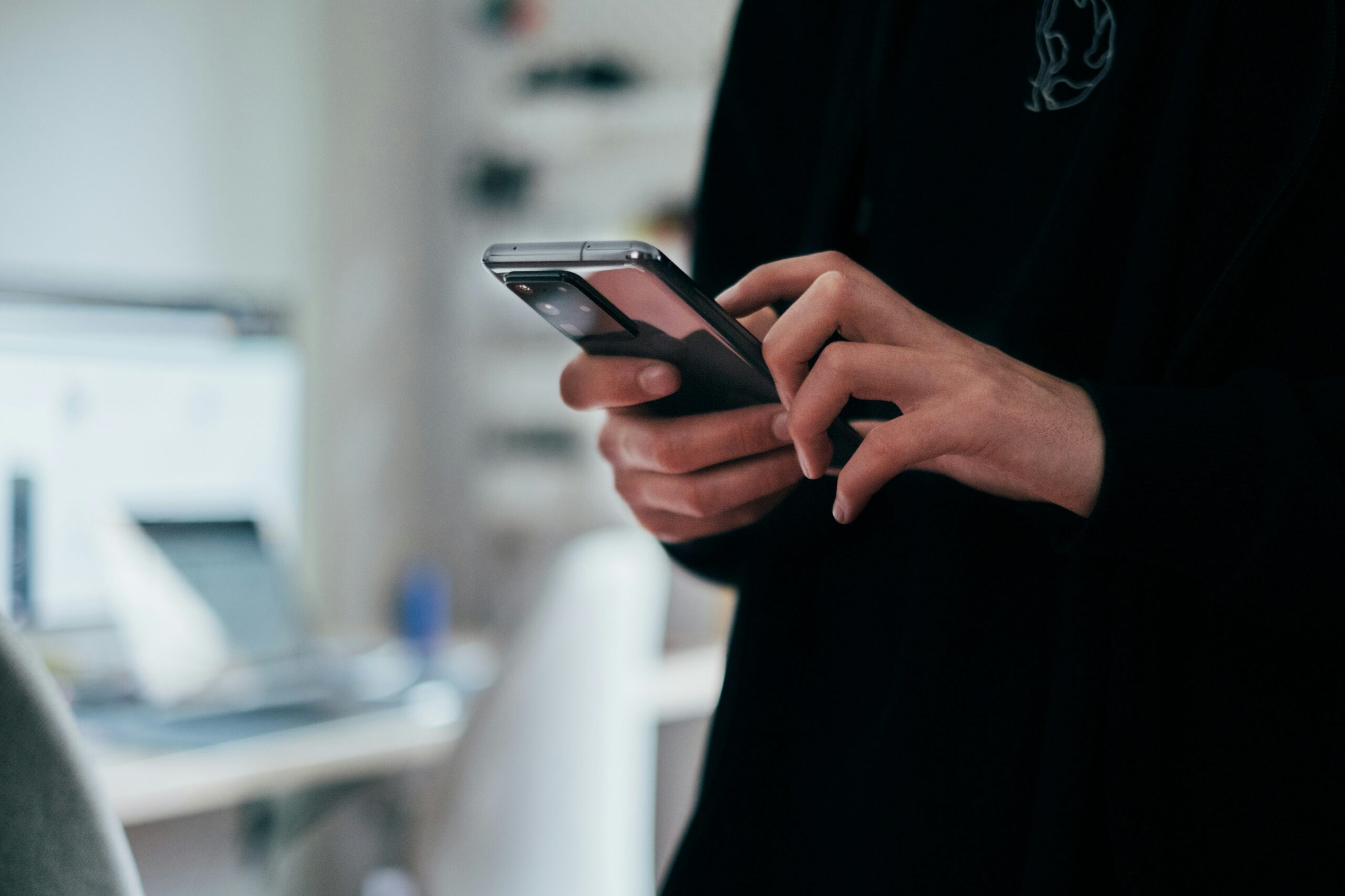 Close up of hand holding phone in an office setting